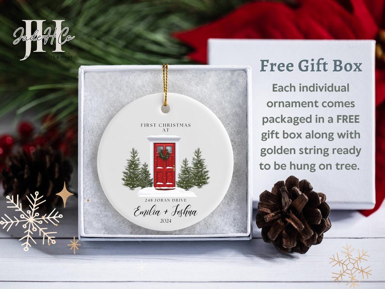 May include: White ceramic Christmas ornament with a red door, green trees, and the text "First Christmas at 248 Joban Drive Emilia + Jeshua 2024".