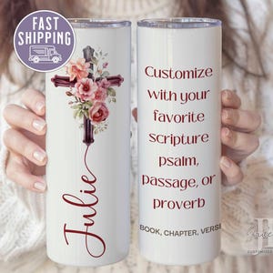 May include: White stainless steel tumbler with a floral cross design and the name "Julie" on the left side. The right side has the text "Customize with your favorite Scripture psalm, passage, or proverb BOOK, CHAPTER, VERSE".