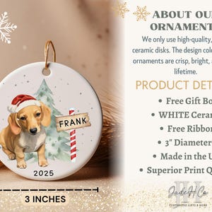 May include: A white ceramic Christmas ornament featuring a dachshund wearing a Santa hat, with a sign that reads "FRANK". The ornament is 3 inches in diameter and includes a Christmas tree and the year 2025.