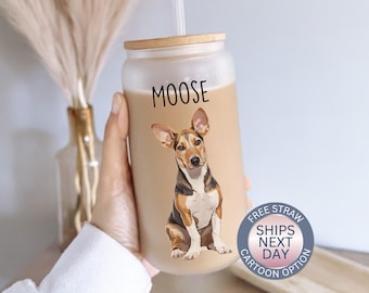 May include: A clear reusable tumbler with a brown lid and a straw. The tumbler has a cartoon image of a brown and white dog with the word "MOOSE" printed on the front.