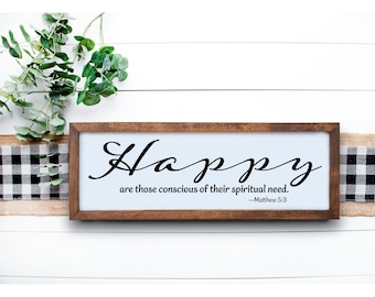 May include: A wooden framed sign with the word "Happy" in elegant black script. The sign includes the quote "are those conscious of their spiritual need." and is decorated with greenery and a buffalo check ribbon.