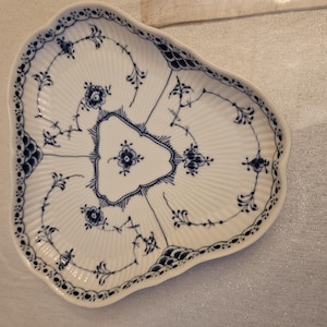 May include: White porcelain serving dish with a unique, three-sectioned design. The dish features a scalloped edge and is decorated with blue floral and vine patterns. The center section has a triangular shape.
