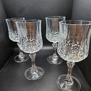 May include: Four clear glass wine glasses with a diamond pattern. The glasses have a tall, slender stem and a round bowl.