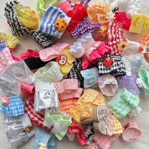 May include: A large collection of colorful hair scrunchies with various patterns and embellishments, including gingham, stripes, lace, and floral designs.