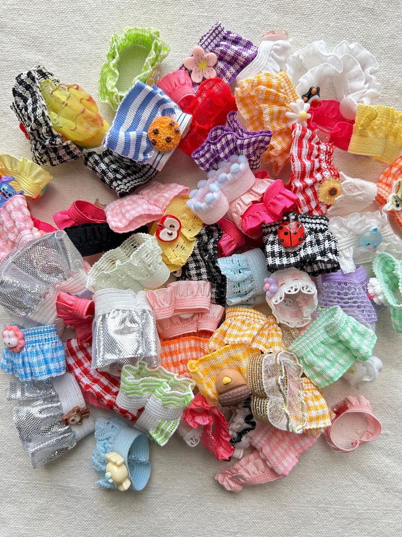 May include: A large collection of colorful hair scrunchies with various patterns and embellishments, including gingham, stripes, lace, and floral designs.