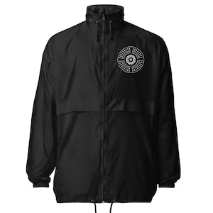 May include: Black windbreaker jacket with a full-length zip, a high collar, and a drawstring hem. A white circular logo is on the left chest. The jacket has two front pockets and a drawstring hood.
