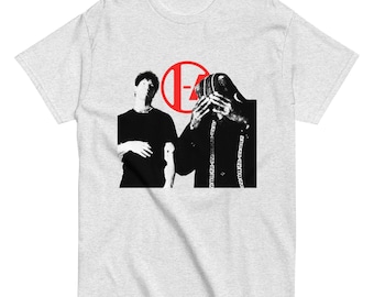 May include: A light gray t-shirt featuring a black and white graphic of two people and a red circle with the letters "I-A". One person is wearing a black shirt and the other is wearing a black hooded garment.