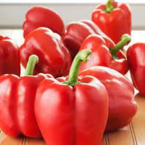 May include: A group of ten red bell peppers, some with stems, on a wooden surface.