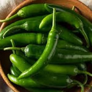 May include: A bowl filled with bright green chili peppers. The peppers are arranged in a random pattern, with some overlapping. The bowl is made of wood and has a natural finish.