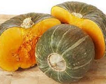 Könnte beinhalten: Drei ganze und halbierte grüne und orangefarbene Kürbisse. Die Kürbisse liegen auf einer Holzoberfläche.