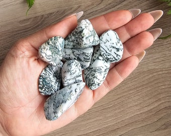 May include: A collection of tumbled green and white moss agate stones. The stones are smooth and polished, with a variety of shapes and sizes.