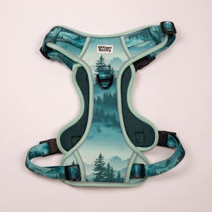 Op de afbeelding: Een teal en groene hondentuig met een berg- en bosontwerp. De tuig heeft verstelbare bandjes en zwarte gespen. De tekst "Officer Sniffy" is op de voorkant gedrukt.