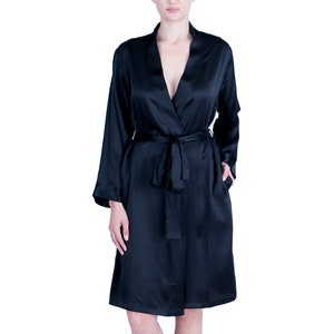 May include: A black satin robe with long sleeves and a waist tie. The robe has a V-neck and pockets. The model is wearing the robe.
