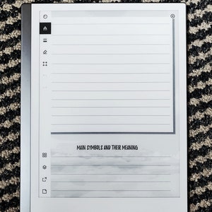 K&ouml;nnte beinhalten: Ein wei&szlig;er E-Reader mit schwarzem Rand und grauem Hintergrund. Der Bildschirm zeigt eine linierte Seite mit dem Text "Main Symbols and Their Meaning".