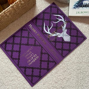 May include: A purple book cover with a chain pattern and a stag illustration. The book is titled "Harry Potter and the Prisoner of Azkaban". The text "I solemnly swear that I am up to no good" is also visible.