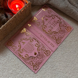 May include: A white ceramic mug with a black handle and the text "But First, Coffee" in a bold, black font. The mug is set against a blurred background. The mug appears to be approximately 10 cm tall.