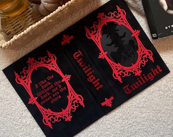 May include: Black book cover with red gothic-style text and design elements. The word "Twilight" is prominently displayed. One side features a quote: "I like the dark. Without the dark, we'd never see the stars."