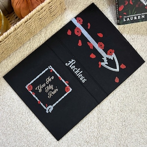 Può includere: Copertina di libro nera con la parola "Reckless" in corsivo bianco. Una freccia argentata con rose rosse e petali è presente. La frase "You Are My Ruin" è all'interno di un diamante argentato a catena.