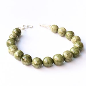 Op de afbeelding: Een armband van groene jade met een zilveren sluiting en kralen.