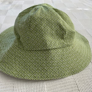 May include: A green bucket hat with a black and white geometric pattern.