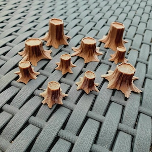 May include: A collection of ten miniature brown wooden tree stumps of varying sizes, arranged on a grey woven surface.