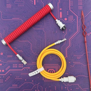 May include: A close-up of three coiled cables. The first cable is red and coiled in a spiral shape. The second cable is yellow and coiled in a circle. The third cable is a long, thin, red cable with a spiral design.