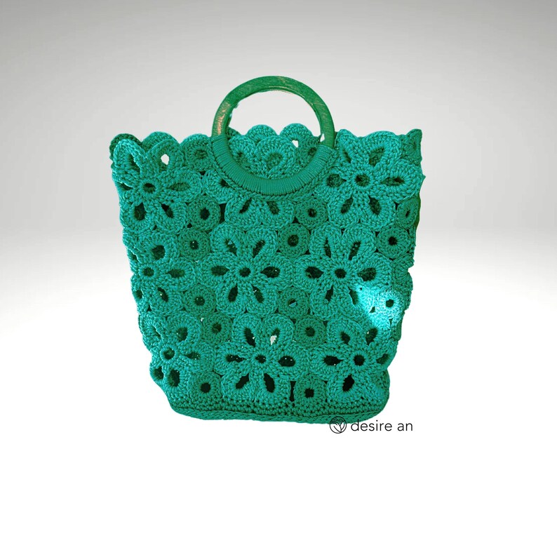 May include: A teal crocheted tote bag with a wooden handle. The bag is made of a delicate, open-weave pattern with a floral design.
