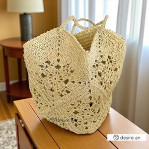 May include: A beige crochet tote bag with a floral design. The bag features two handles and a wide opening. It's crafted from light-coloured yarn, giving it a textured look. The bag is placed on a wooden surface.