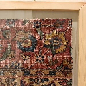 Pu&ograve; includere: Un frammento di tappeto vintage incorniciato con sfondo rosso e intricati motivi floreali in tonalit&agrave; di blu, verde e giallo.