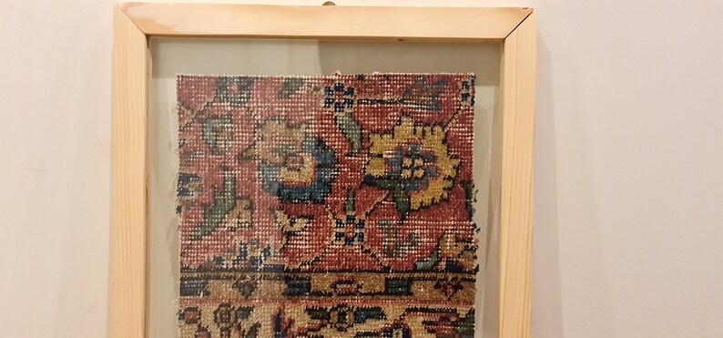 Pu&ograve; includere: Un frammento di tappeto vintage incorniciato con sfondo rosso e intricati motivi floreali in tonalit&agrave; di blu, verde e giallo.