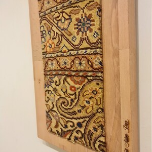 May include: A framed vintage rug with a colorful floral pattern. The frame is made of light wood and has the text "Wall Kilim Rug" engraved on the bottom right corner.
