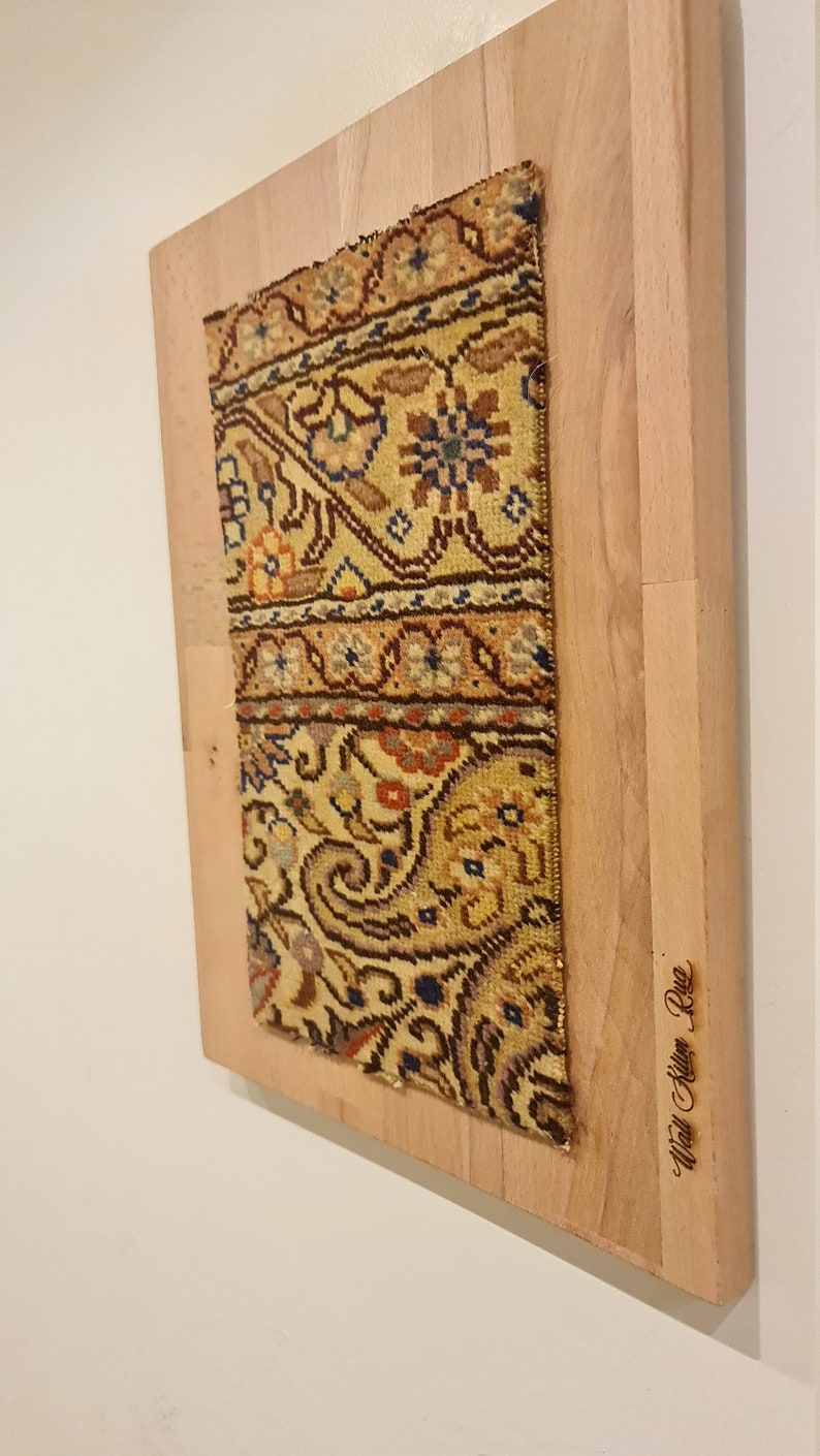 May include: A framed vintage rug with a colorful floral pattern. The frame is made of light wood and has the text "Wall Kilim Rug" engraved on the bottom right corner.
