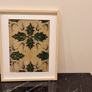 May include: A framed print of a vintage rug with a green and beige floral pattern.