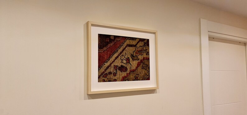 May include: A framed print of a close-up of a colorful rug with intricate patterns.