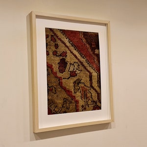 May include: A framed print of a close-up of a colorful rug with intricate patterns in shades of red, brown, and gold.