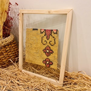 Puede incluir: Un trozo de tela con estampado amarillo y rojo enmarcado con un marco de madera. La tela es un primer plano de un trozo de tela m&aacute;s grande.