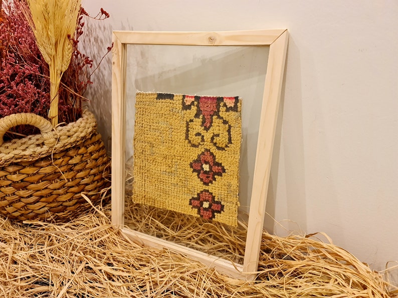 Puede incluir: Un trozo de tela con estampado amarillo y rojo enmarcado con un marco de madera. La tela es un primer plano de un trozo de tela m&aacute;s grande.