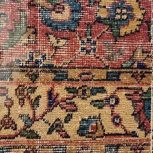 Pu&ograve; includere: Un tappeto incorniciato con un motivo floreale dettagliato in tonalit&agrave; di rosso, blu, verde e giallo. Il tappeto &egrave; incorniciato in una cornice di legno chiaro.