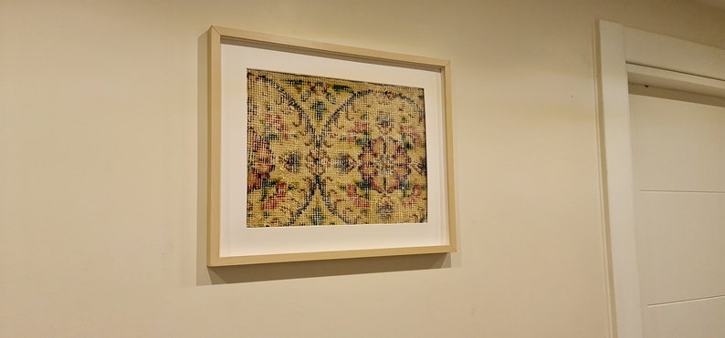May include: A framed print of a vintage rug with a floral pattern in shades of yellow, red, blue, and green.