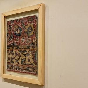 Pu&ograve; includere: Un'opera d'arte incorniciata che presenta un tappeto colorato con motivi intricati in tonalit&agrave; di rosso, blu e giallo.