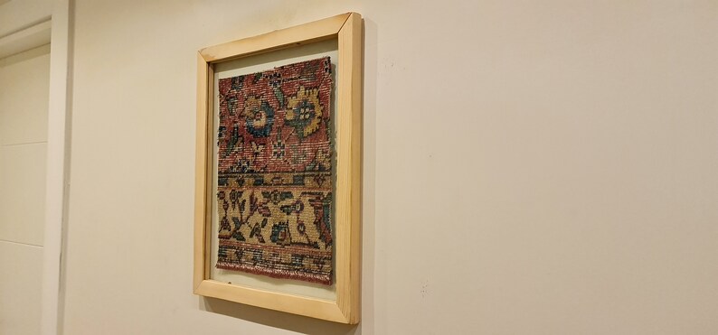 Pu&ograve; includere: Un'opera d'arte incorniciata che presenta un tappeto colorato con motivi intricati in tonalit&agrave; di rosso, blu e giallo.