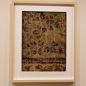 May include: A framed print of a vintage rug with a green, brown, and red floral pattern.