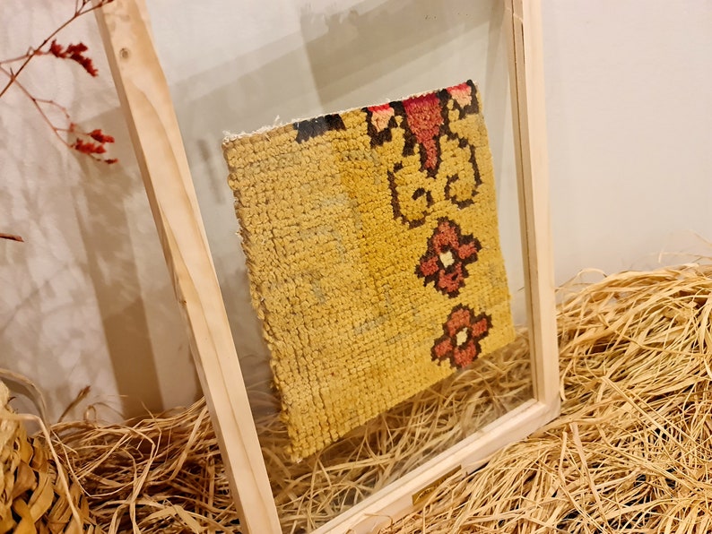 Puede incluir: Un trozo de tela amarilla enmarcado con un patr&oacute;n floral rojo y negro. La tela se muestra en un lecho de paja.