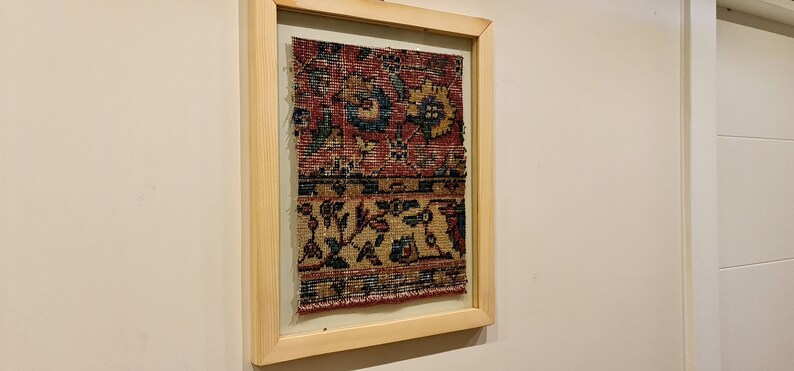 Pu&ograve; includere: Un pezzo di tessuto antico incorniciato con un motivo floreale colorato in tonalit&agrave; di rosso, blu e giallo. Il tessuto &egrave; tessuto con dettagli intricati e ha un bordo sfrangiato.