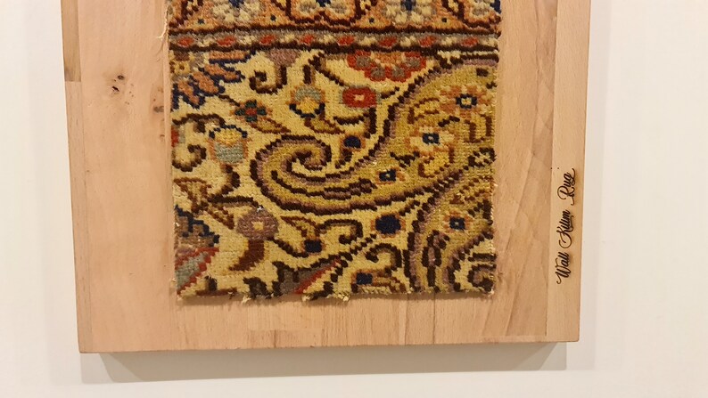 May include: A close-up of a colorful rug with intricate floral patterns, mounted on a wooden frame. The frame is labeled "Wall Art Rug".