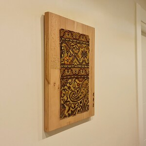 May include: A framed piece of antique fabric with a colorful paisley pattern, mounted on a wooden frame.