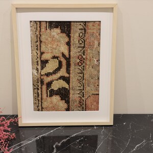 K&ouml;nnte beinhalten: Ein gerahmter Druck eines Vintage-Teppichs mit einem floralen Design in Braun-, Beige- und Rott&ouml;nen.