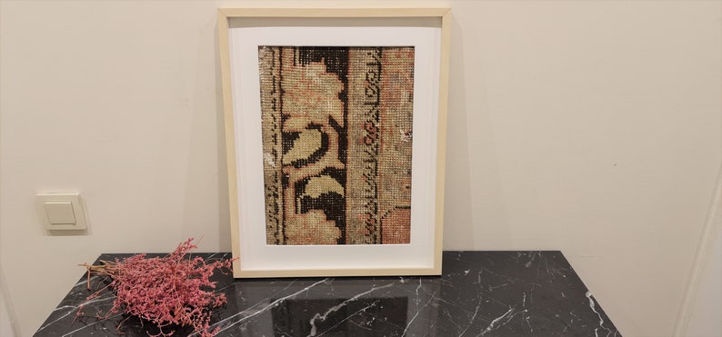 K&ouml;nnte beinhalten: Ein gerahmter Druck eines Vintage-Teppichs mit einem floralen Design in Braun-, Beige- und Rott&ouml;nen.