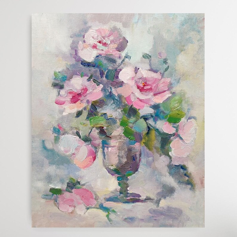 May include: A painting of a bouquet of pink roses in a clear glass vase. The roses are arranged in a loose, natural style, and the vase is set on a table with a white tablecloth. The background is a soft, muted blue.