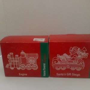 May include: Two red boxes with green accents. One box features a white outline of a train engine and the word "Engine". The other box shows Santa in a sleigh with the words "Santa's Gift Sleigh".